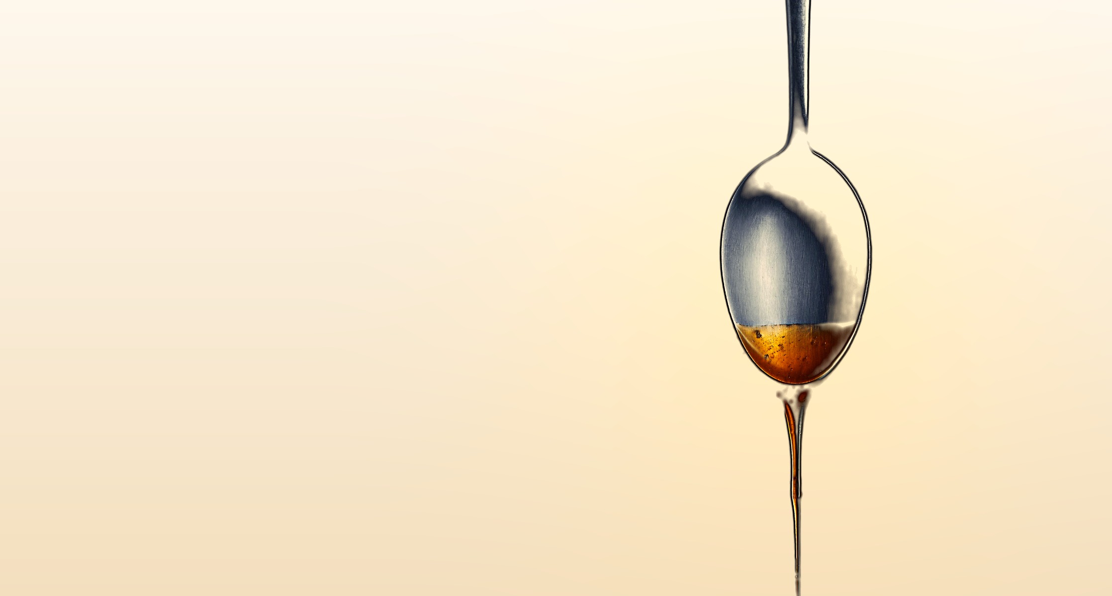 Goldenes Omega-3-Öl auf einem Löffel, aus dem ein Tropfen fällt